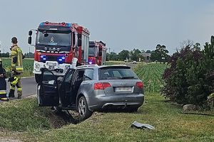 rozbite auto w tle wóz straży pożarnej obok strażak