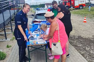 funkcjonariuszka przy stoisku policyjnym rozmawia z uczestnikami pikniku