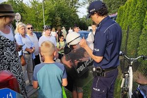 policjant pomaga chłopcu założyć strój szturmowy