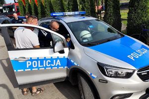 policjant pokazuje dzieciom radiowóz
