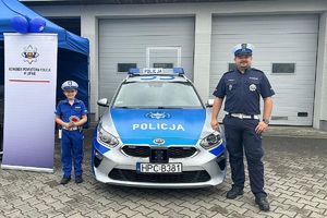 policjant drogówki pozuje przy radiowozie ze swoim synem, który jest w stroju policjanta drogówki