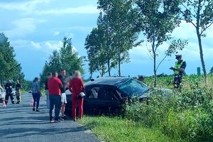 policjant przy bmw sporządza dokumentację do wypadku, obok stoją osoby