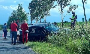 policjant przy bmw sporządza dokumentację do wypadku, obok stoją osoby