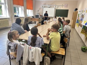 Policjantka opowiada dzieciom o bezpieczeństwie. Dzieci siedzą w ławkach.
