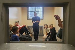 policjantka pokazuje przybyłym pomieszczenia dla osób zatrzymanych