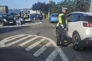 policjant bada trzeźwość kierowcy, w tle inny policjant rozmawia z zatrzymaną kobietą