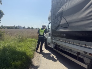 Policjant prowadzi kontrole drogową, rozmawia z kierowcą