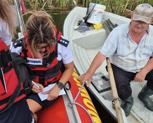 Policjantka legitymuje mężczyznę pływającego łódką