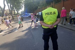 policjant zatrzymał ruch w rejonie szkoły by uczniowie bezpiecznie przeszli przez przejście