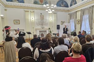 lektor przemawia, na pierwszym planie goście siedzący na sali