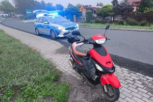 motorower, za nim radiowóz z włączonymi światłami błyskowymi
