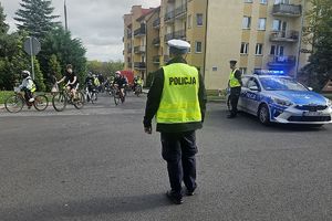 policjant kierujący ruchem na skrzyżowaniu - w tle uczestnicy rajdu
