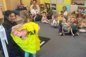 dziewczynka przymierza odblaskową kamizelkę policyjną