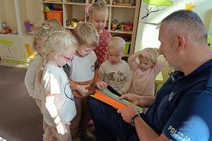 policjant wręcza dzieciom odblaskowe opaski