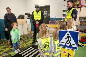 policjanci z dziećmi ćwiczą w miasteczku ruchu drogowego