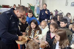 policjant rozdaje dzieciom odblaskowe zawieszki