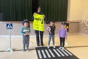 policjantka pokazuje dzieciom kamizelkę odblaskową