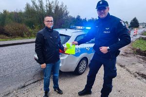 policjant wręcza pieszemu kamizelkę odblaskową