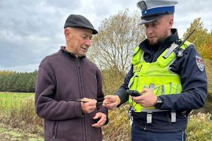 policjant wręcza mężczyźnie opaskę odblaskową