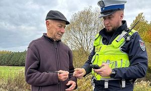 policjant wręcza mężczyźnie opaskę odblaskową