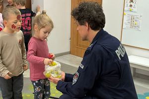 policjant rozdaje dzieciom odblaskowe zawieszki