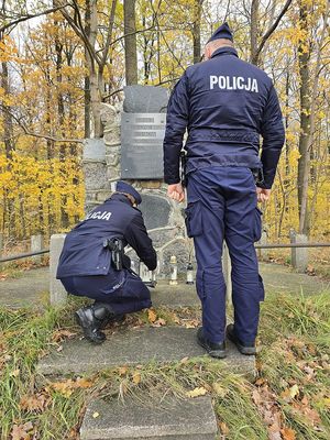 policjanci stawiają znicz przy pomniku