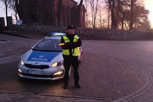 policjant z czerwoną latarką przy radiowozie