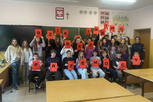 na zdjęciu policjantka z uczniami trzymającymi napis "Dzieciństwo bez przemocy"