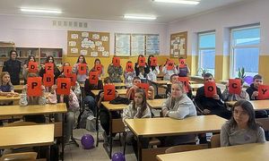 na zdjęciu policjantka z uczniami trzymającymi napis &quot;Dzieciństwo bez przemocy&quot;