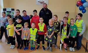 policjant z dziećmi z odblaskowymi elementami