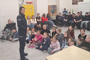 policjantka prowadząca spotkanie w tle uczniowie