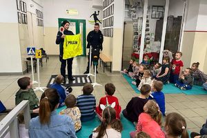 policjantka pokazuje dzieciom kamizelkę odblaskową