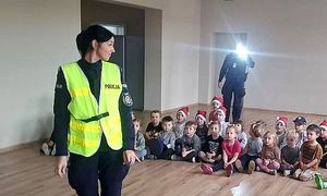 policjantka pokazuje dzieciom kamizelkę odblaskową