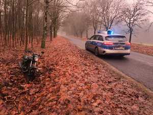 Radiowóz stojący na drodze i motorower w rowie.