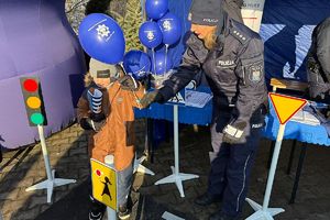 policjantka wręcza dziecku granatowy balonik policyjny
