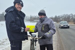 policjant wręcza rowerzyście kamizelkę odblaskową