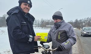 policjant wręcza kamizelkę odblaskową rowerzyście