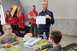 policjantka pokazuje dzieciom kolorowankę profilaktyczną