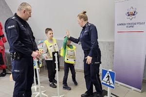 chłopcy w kamizelkach odblaskowych przybijają "piątkę" z policjantką