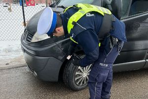 policjant kontroluje stan ogumienia pojazdu