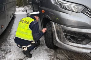 policjant kontroluje stan ogumienia pojazdu