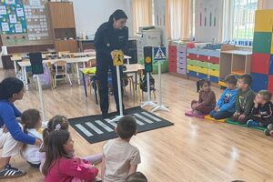 policjantka pokazuje dzieciom znaki drogowe
