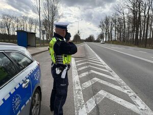 Policjant stoi na drodze i mierzy prędkość