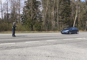 Policjant stoi i na drodze i zatrzymuje pojazd do kontroli