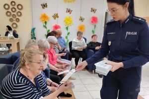 policjantka rozdaje seniorom ulotki