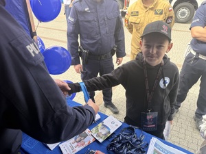 Policjant zakłada dziecku opaskę odblaskową