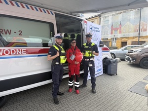 Policjanci ruchu drogowego stoą z ratownikiem WOPR