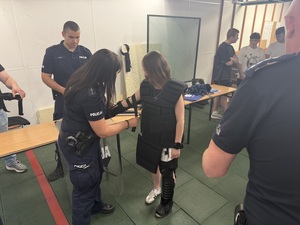 Policjantka ubiera uczestniczkę w strój Oddziałów Prewencji