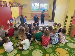 Policjantka siedzi i opowiada dzieciom o bezpieczeństwie.