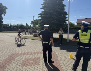 Uczennica pokonuje tor rowerem. Policjanci stoją i patrzą.